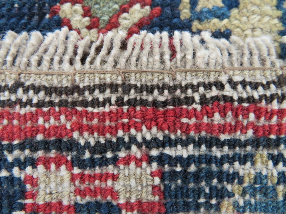 A long, narrow hand-knotted wool runner featuring a repeating geometric Mina Khana floral lattice pattern in navy blue, terracotta red, and cream tones. View XXI