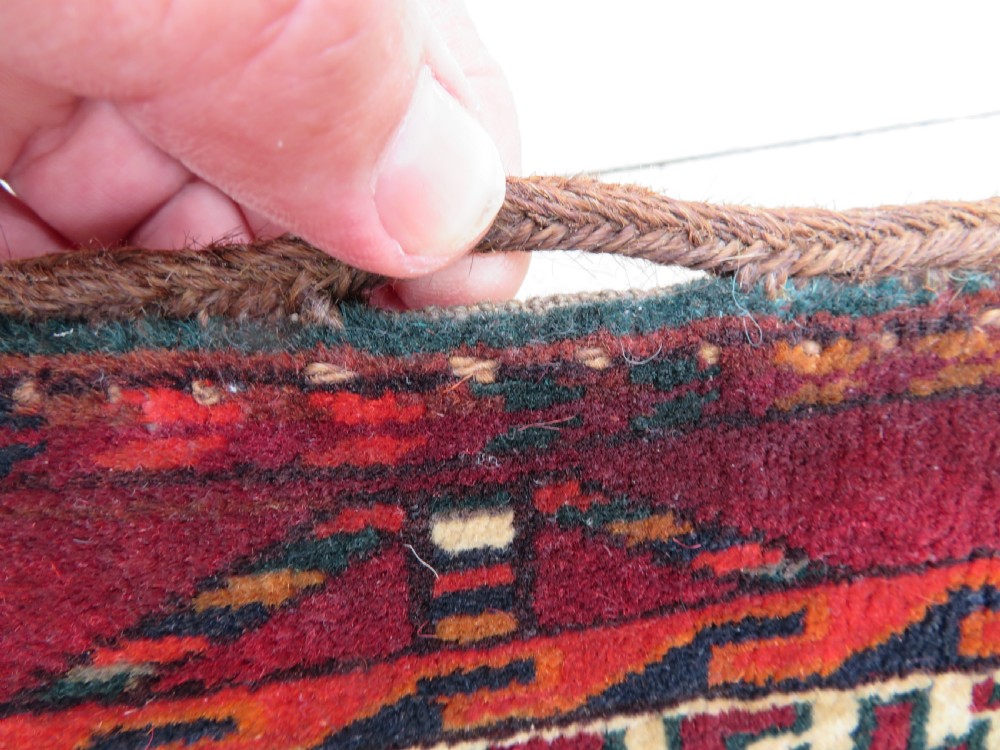 An antique woven Yomut Turkmen chuval rug in deep red wool featuring nine central geometric gul motifs surrounded by a patterned border and a detailed lower elem panel. View XII