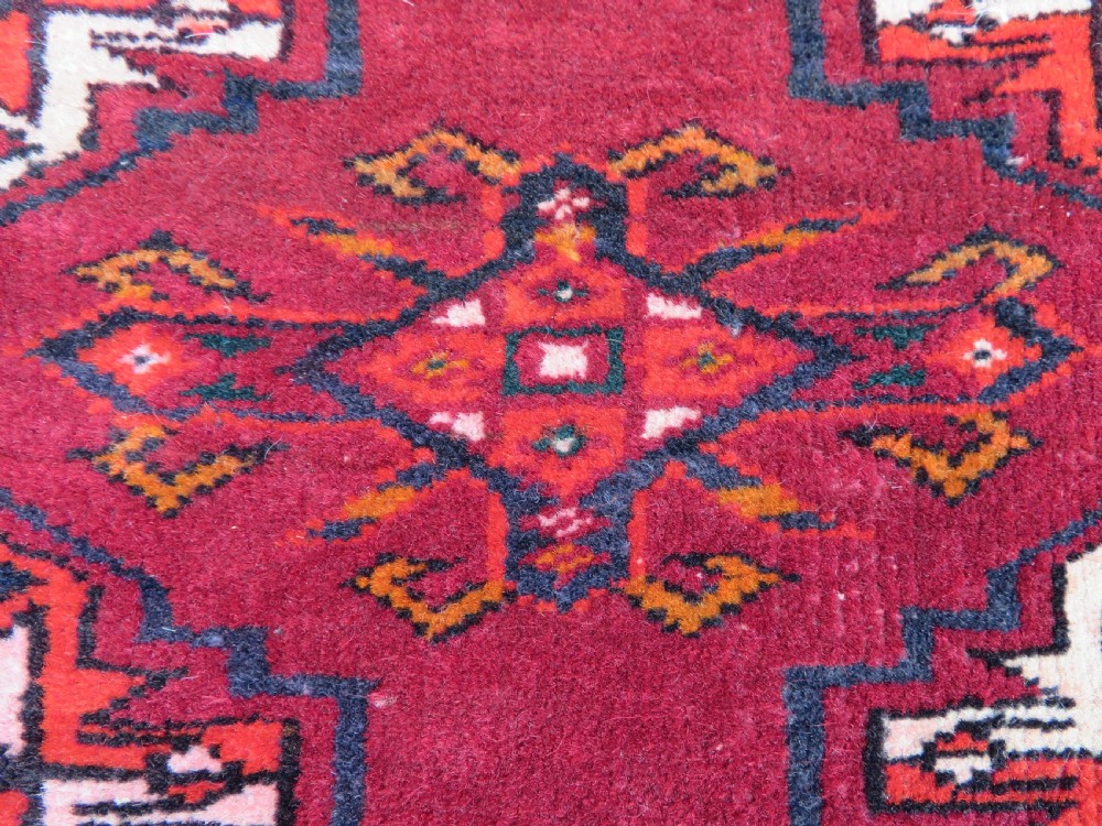 An antique woven Yomut Turkmen chuval rug in deep red wool featuring nine central geometric gul motifs surrounded by a patterned border and a detailed lower elem panel. View XIV