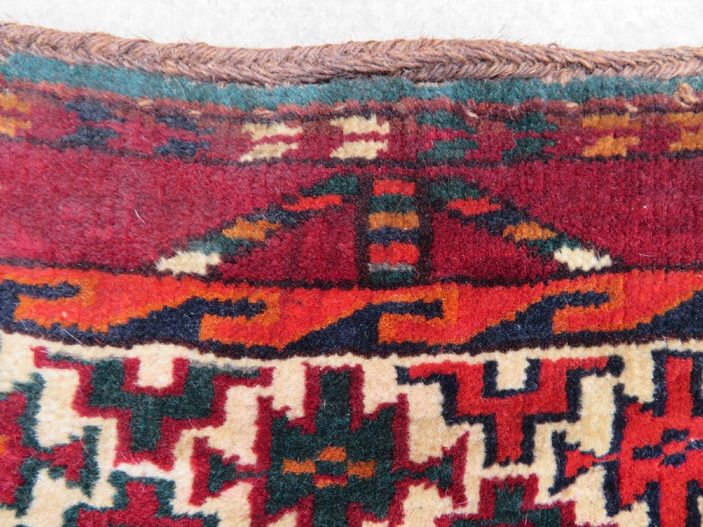 An antique woven Yomut Turkmen chuval rug in deep red wool featuring nine central geometric gul motifs surrounded by a patterned border and a detailed lower elem panel. View XVI