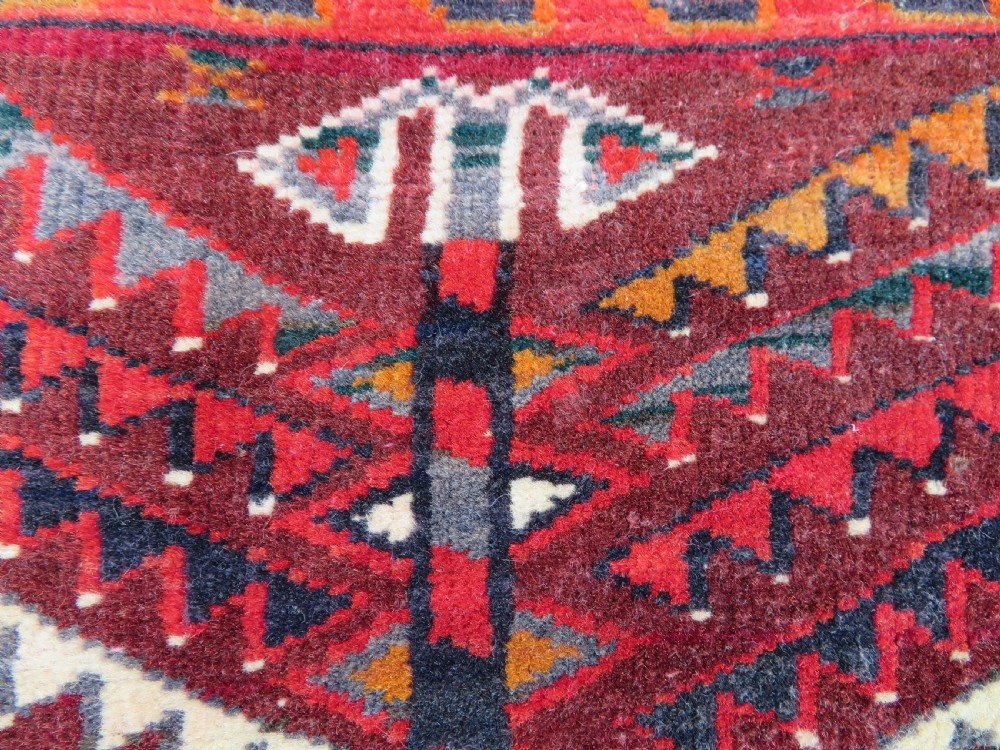 An antique woven Yomut Turkmen chuval rug in deep red wool featuring nine central geometric gul motifs surrounded by a patterned border and a detailed lower elem panel. View XVIII