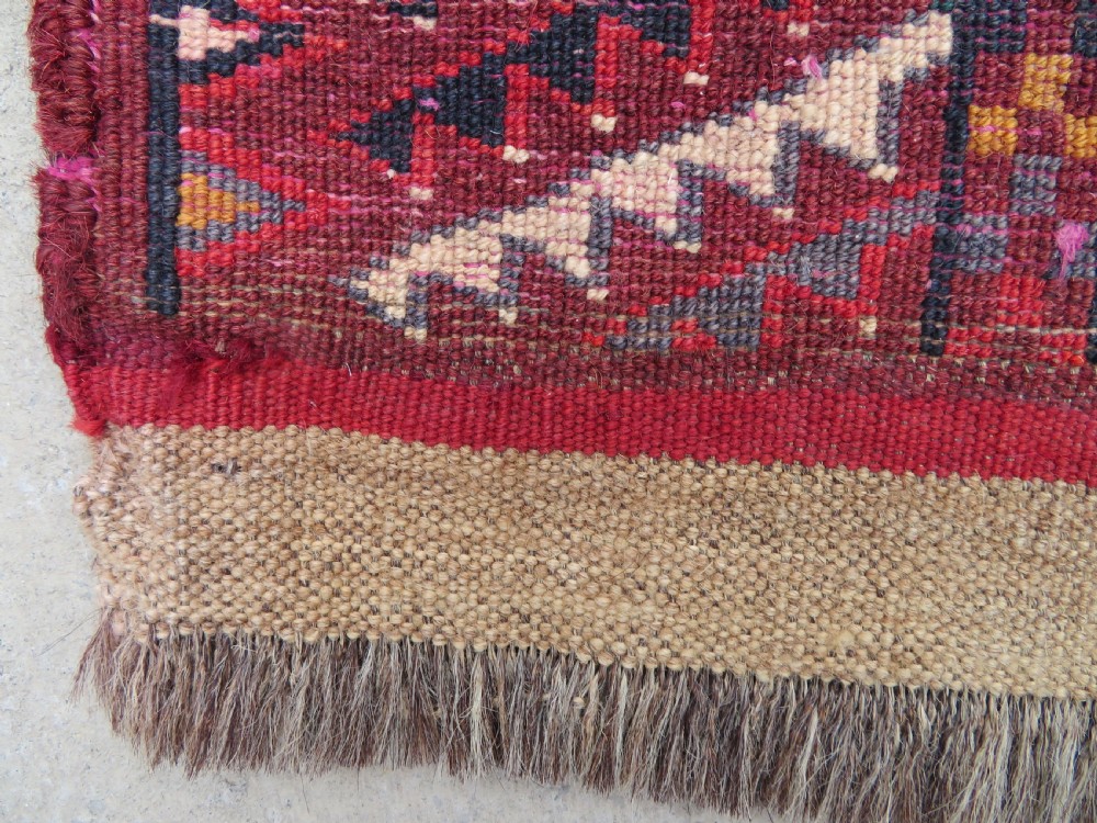 An antique woven Yomut Turkmen chuval rug in deep red wool featuring nine central geometric gul motifs surrounded by a patterned border and a detailed lower elem panel. View XX