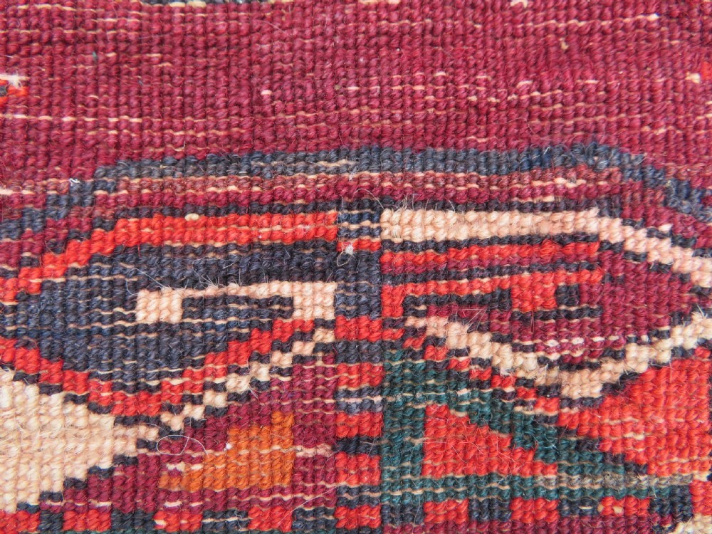 An antique woven Yomut Turkmen chuval rug in deep red wool featuring nine central geometric gul motifs surrounded by a patterned border and a detailed lower elem panel. View XXII