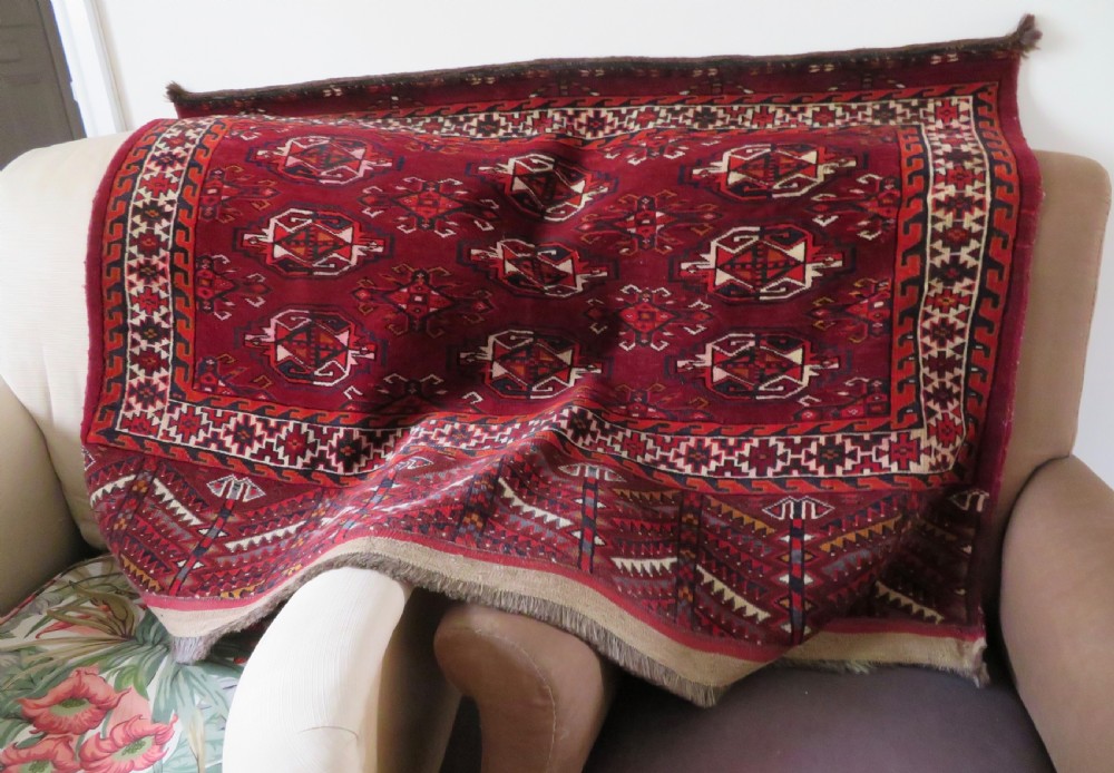 An antique woven Yomut Turkmen chuval rug in deep red wool featuring nine central geometric gul motifs surrounded by a patterned border and a detailed lower elem panel. View XXIII