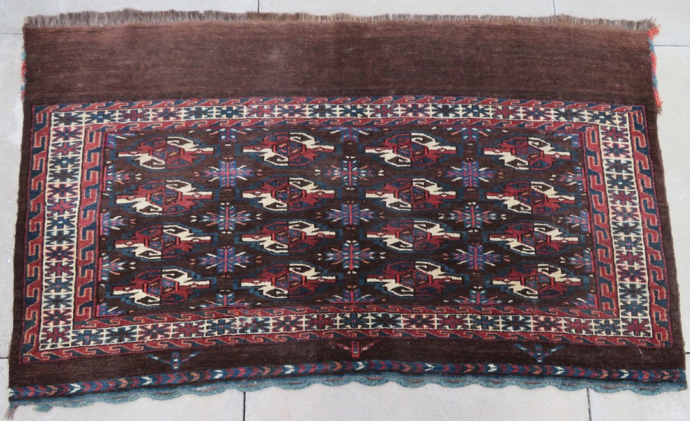 A rectangular hand-woven Yomut Turkmen wool chuval bag face featuring sixteen repeating central guls framed by geometric borders and a solid dark brown lower elem skirt. View II