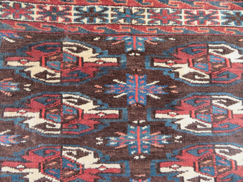 A rectangular hand-woven Yomut Turkmen wool chuval bag face featuring sixteen repeating central guls framed by geometric borders and a solid dark brown lower elem skirt. View IV