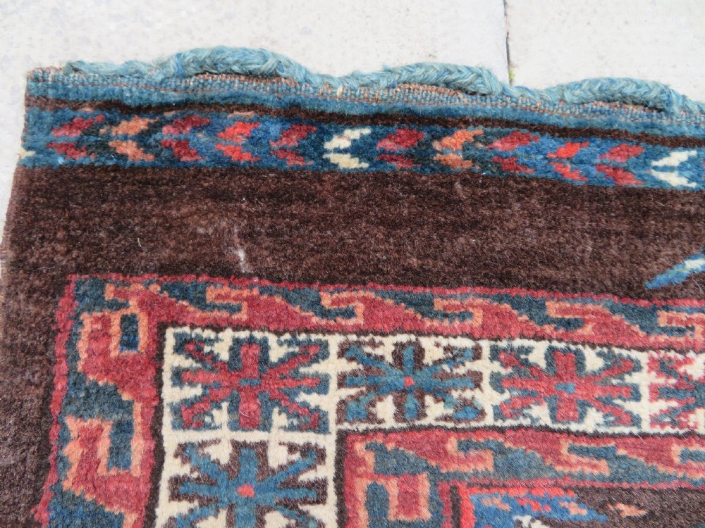 A rectangular hand-woven Yomut Turkmen wool chuval bag face featuring sixteen repeating central guls framed by geometric borders and a solid dark brown lower elem skirt. View V