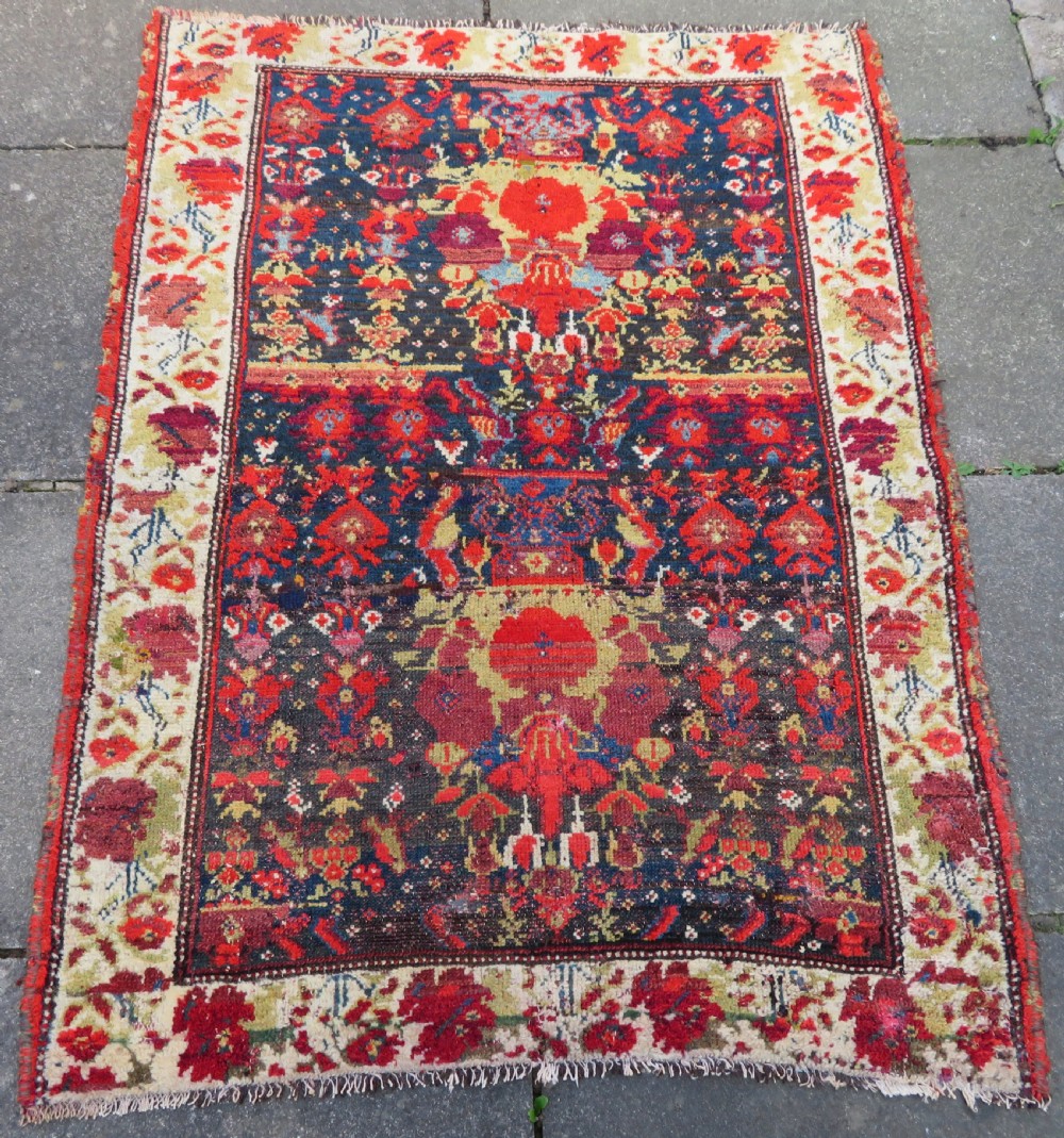 A rectangular hand-knotted antique Kurdish wool rug featuring red, navy blue, and cream tribal motifs with a decorated floral border. View II