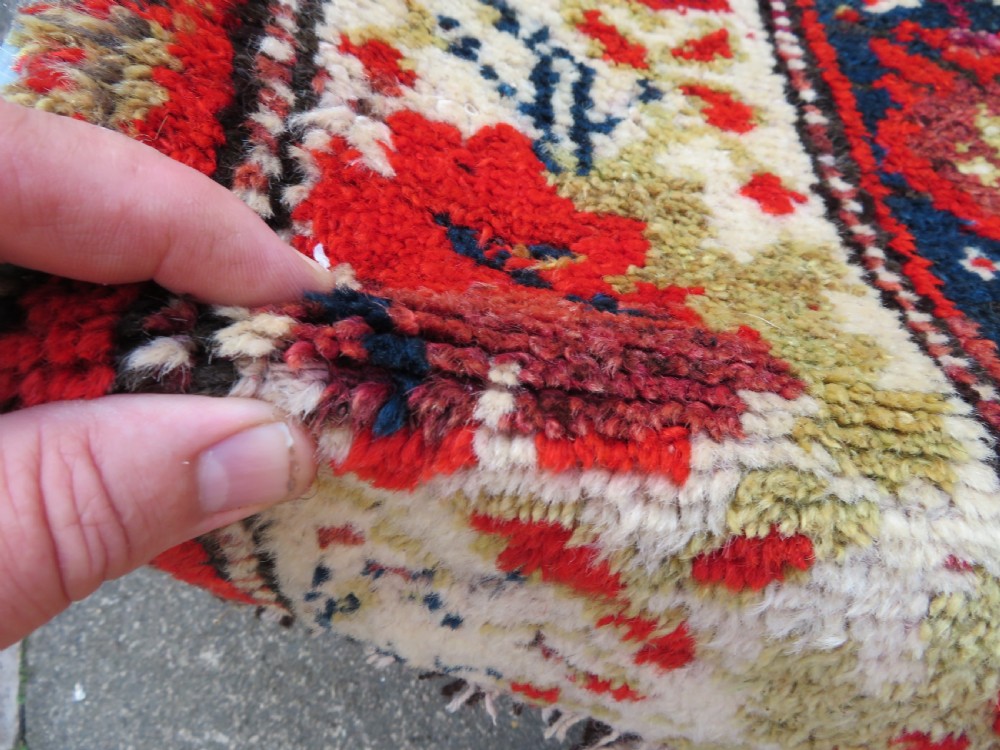 A rectangular hand-knotted antique Kurdish wool rug featuring red, navy blue, and cream tribal motifs with a decorated floral border. View IX