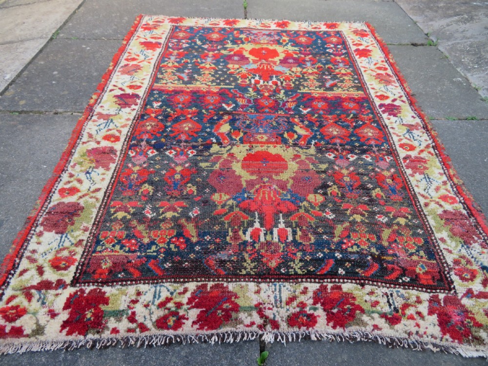 A rectangular hand-knotted antique Kurdish wool rug featuring red, navy blue, and cream tribal motifs with a decorated floral border. View XII
