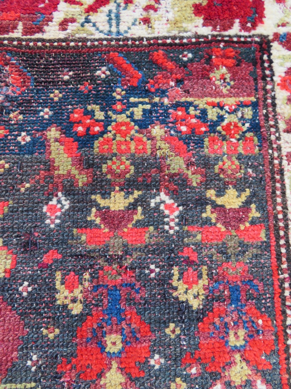 A rectangular hand-knotted antique Kurdish wool rug featuring red, navy blue, and cream tribal motifs with a decorated floral border. View XIV