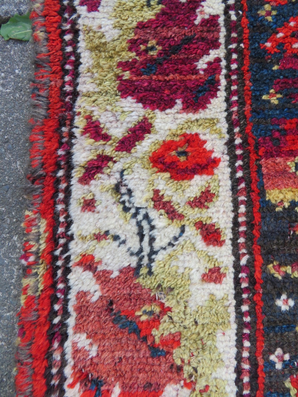 A rectangular hand-knotted antique Kurdish wool rug featuring red, navy blue, and cream tribal motifs with a decorated floral border. View XVI