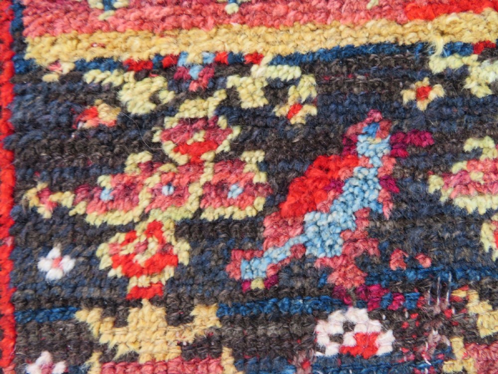 A rectangular hand-knotted antique Kurdish wool rug featuring red, navy blue, and cream tribal motifs with a decorated floral border. View XVII