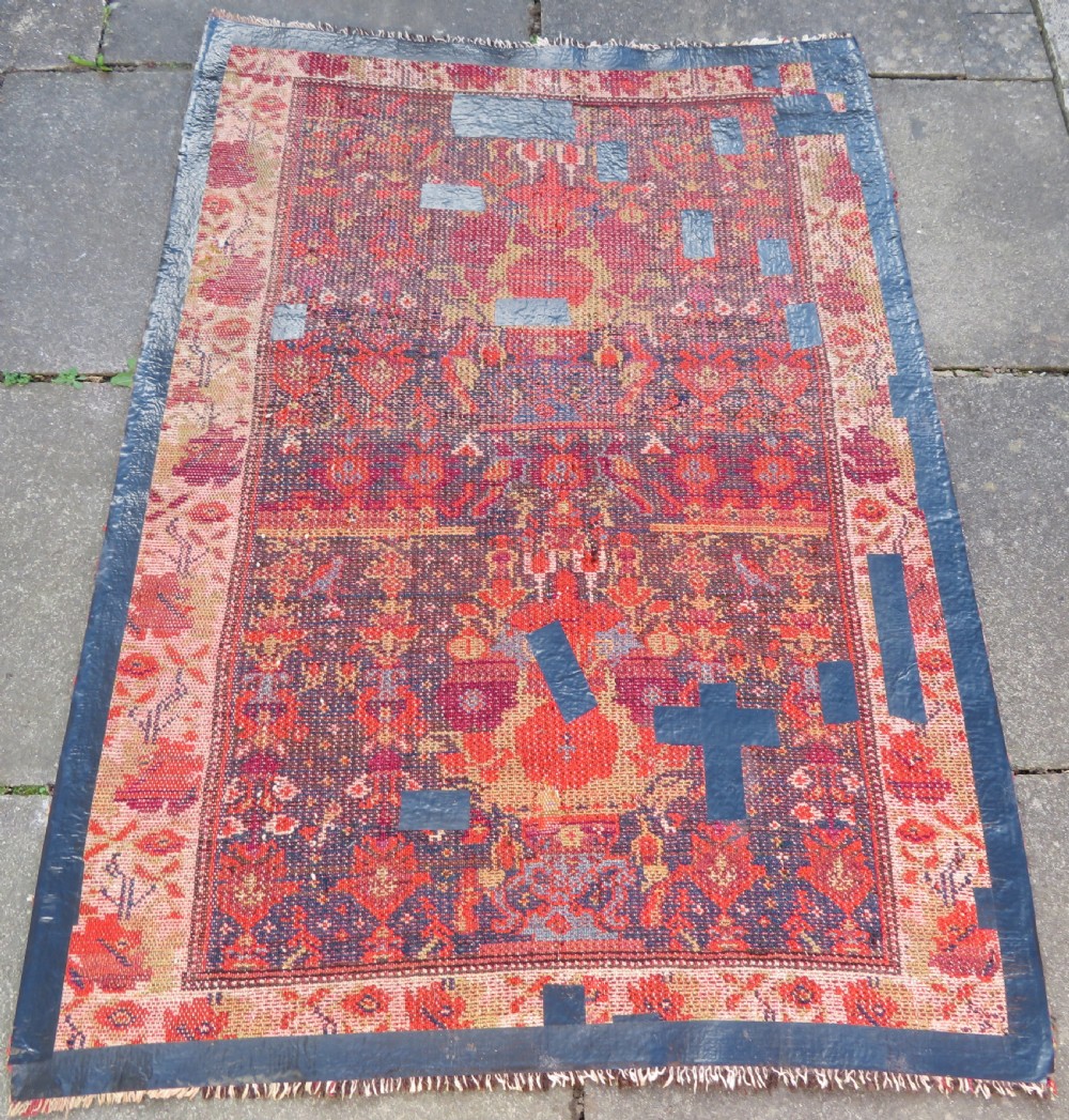 A rectangular hand-knotted antique Kurdish wool rug featuring red, navy blue, and cream tribal motifs with a decorated floral border. View XXV