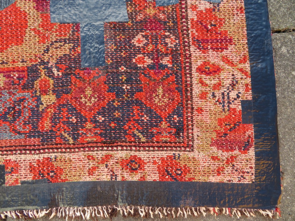 A rectangular hand-knotted antique Kurdish wool rug featuring red, navy blue, and cream tribal motifs with a decorated floral border. View XXVI