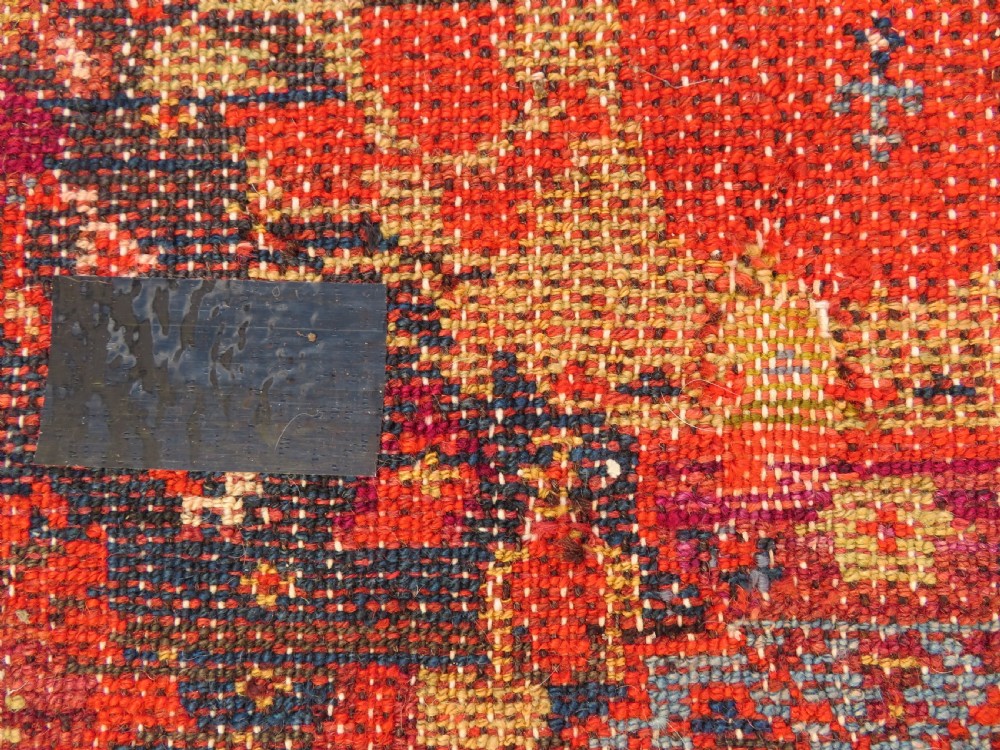 A rectangular hand-knotted antique Kurdish wool rug featuring red, navy blue, and cream tribal motifs with a decorated floral border. View XXVII