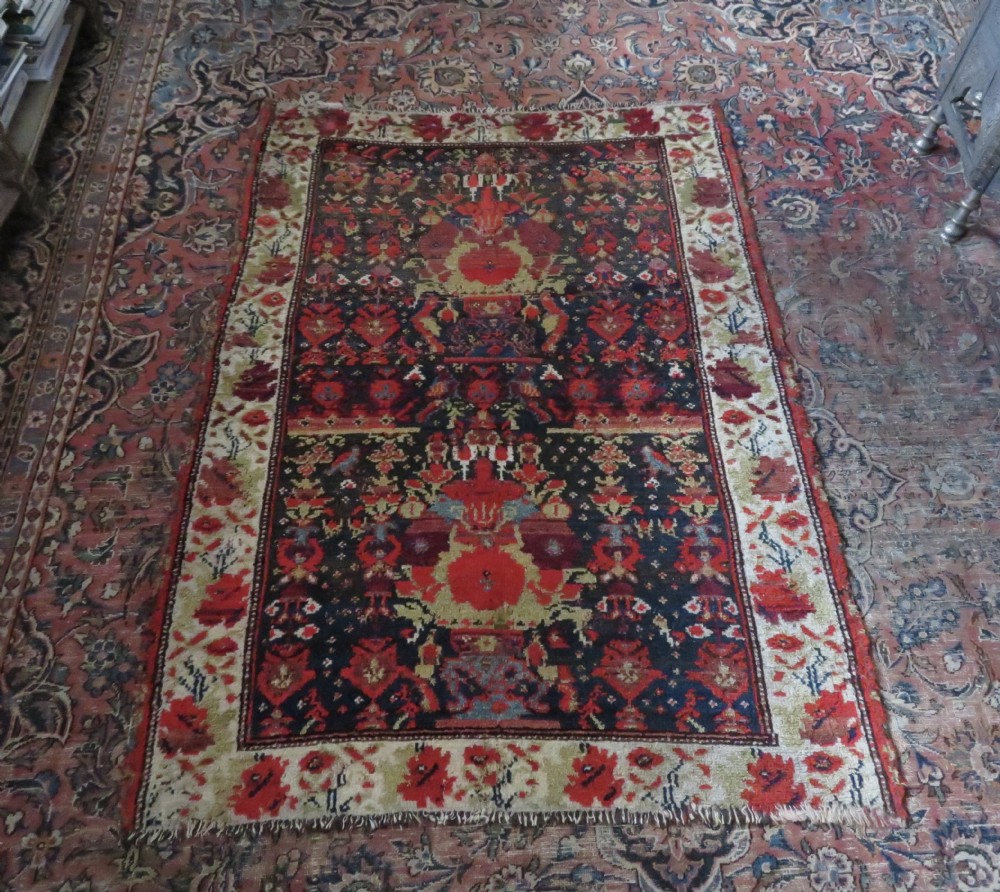 A rectangular hand-knotted antique Kurdish wool rug featuring red, navy blue, and cream tribal motifs with a decorated floral border. View XXIX