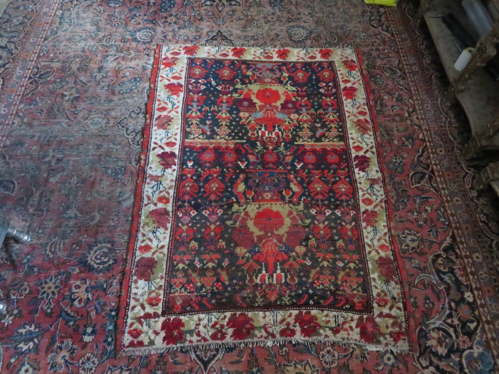 A rectangular hand-knotted antique Kurdish wool rug featuring red, navy blue, and cream tribal motifs with a decorated floral border. View XXX