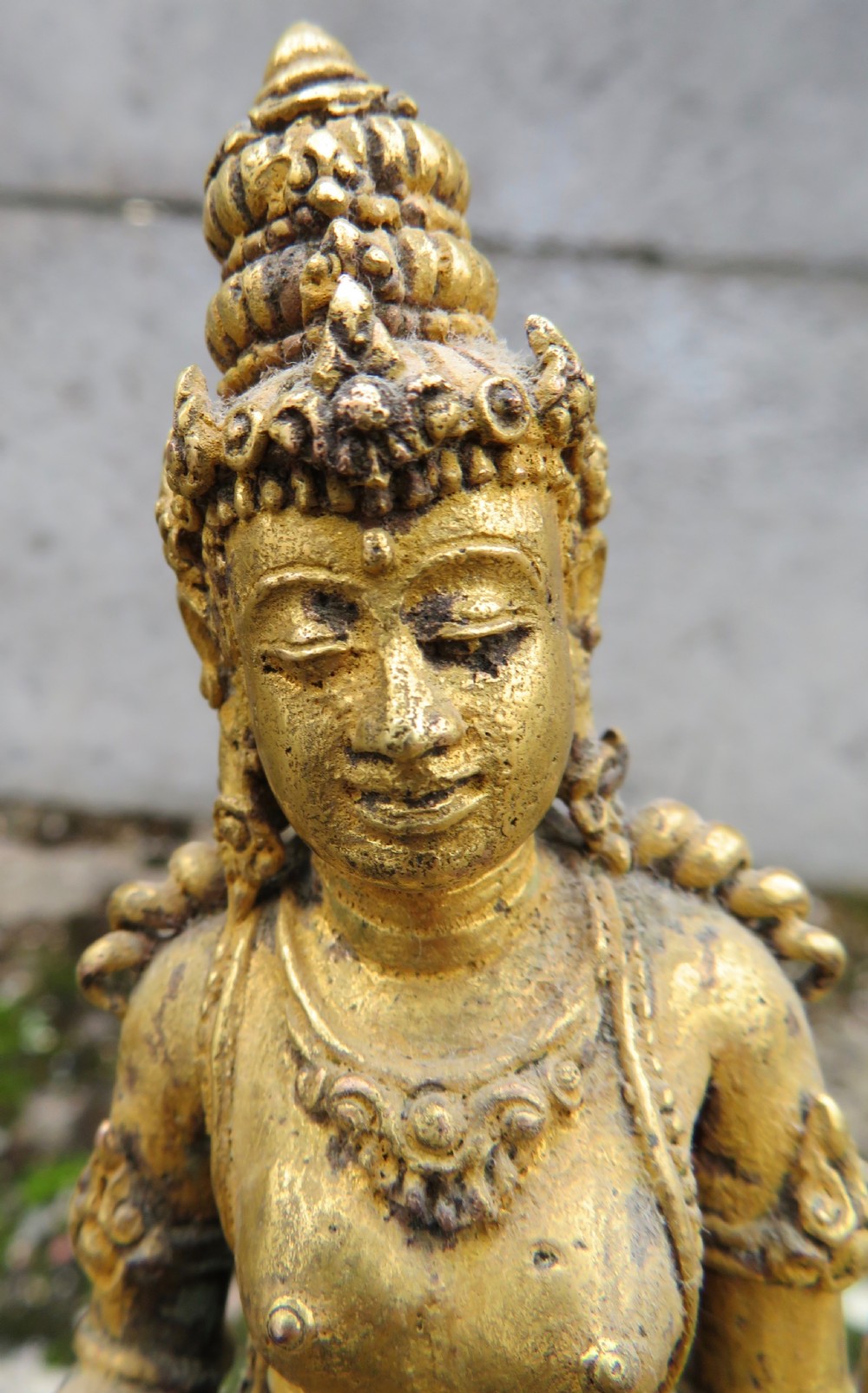 A standing gilded metal statue of a deity on a lotus base holding a lotus stem with an ornate crown and detailed jewellery. View III