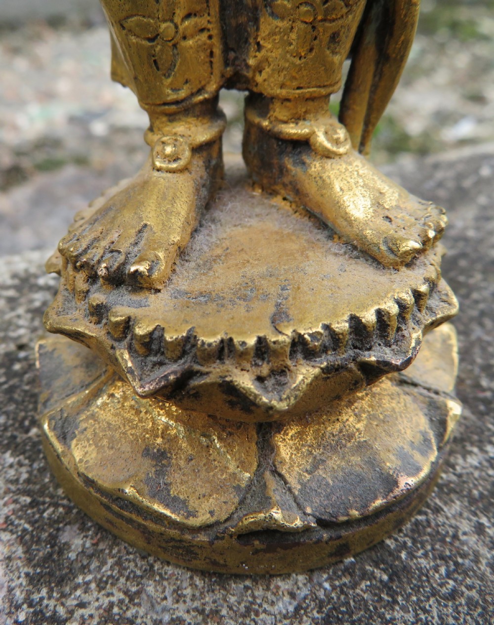 A standing gilded metal statue of a deity on a lotus base holding a lotus stem with an ornate crown and detailed jewellery. View VI