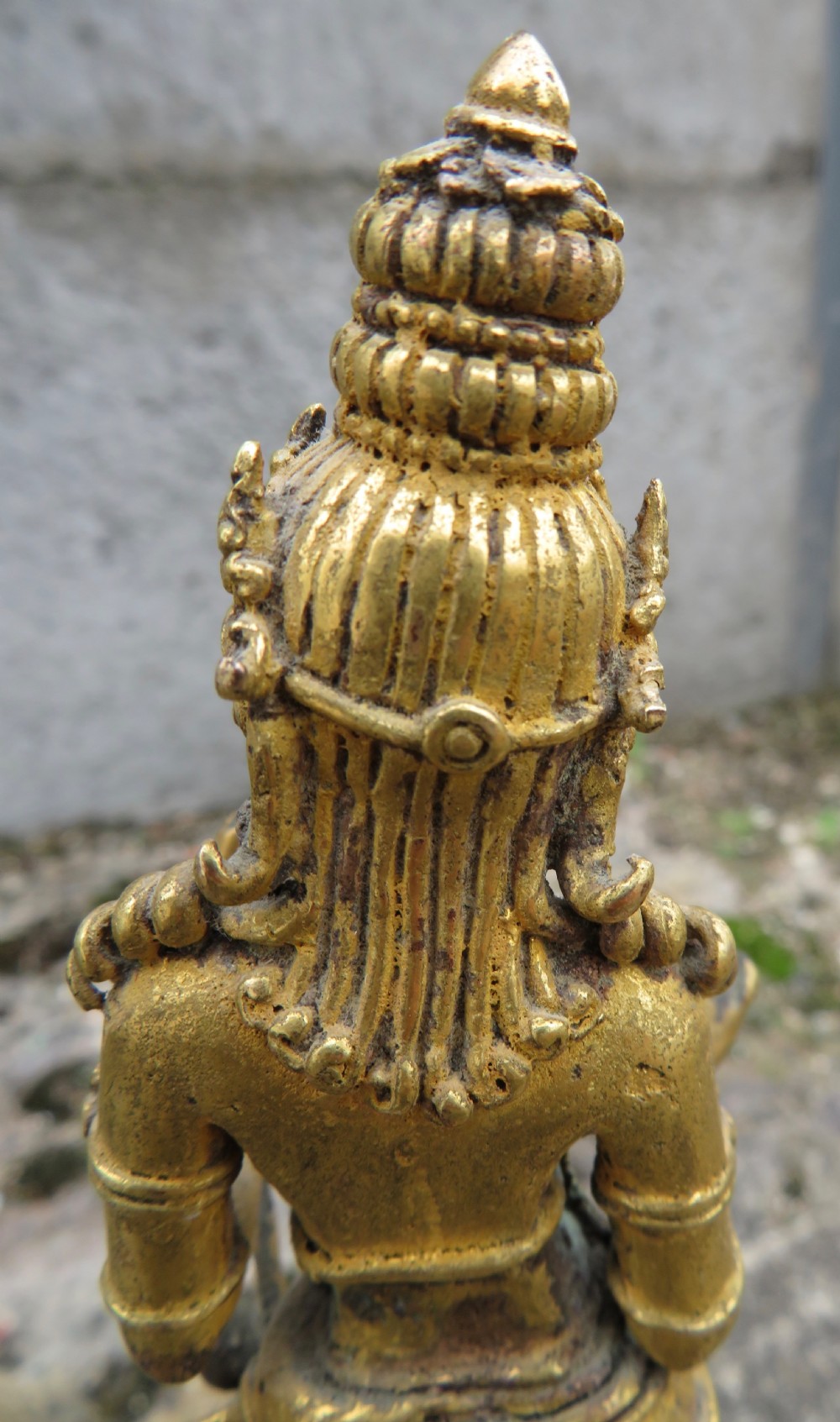 A standing gilded metal statue of a deity on a lotus base holding a lotus stem with an ornate crown and detailed jewellery. View X