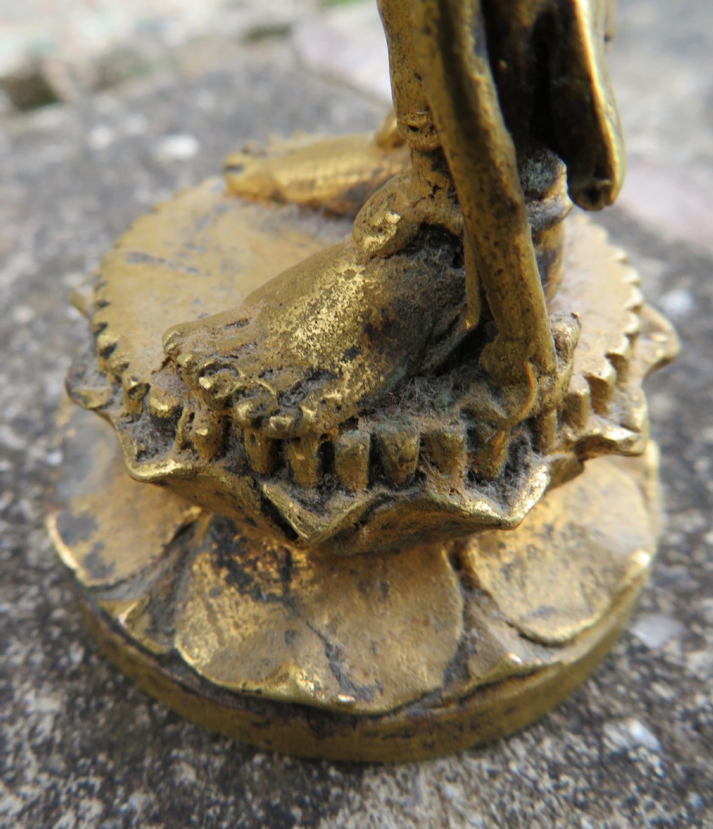 A standing gilded metal statue of a deity on a lotus base holding a lotus stem with an ornate crown and detailed jewellery. View XVI