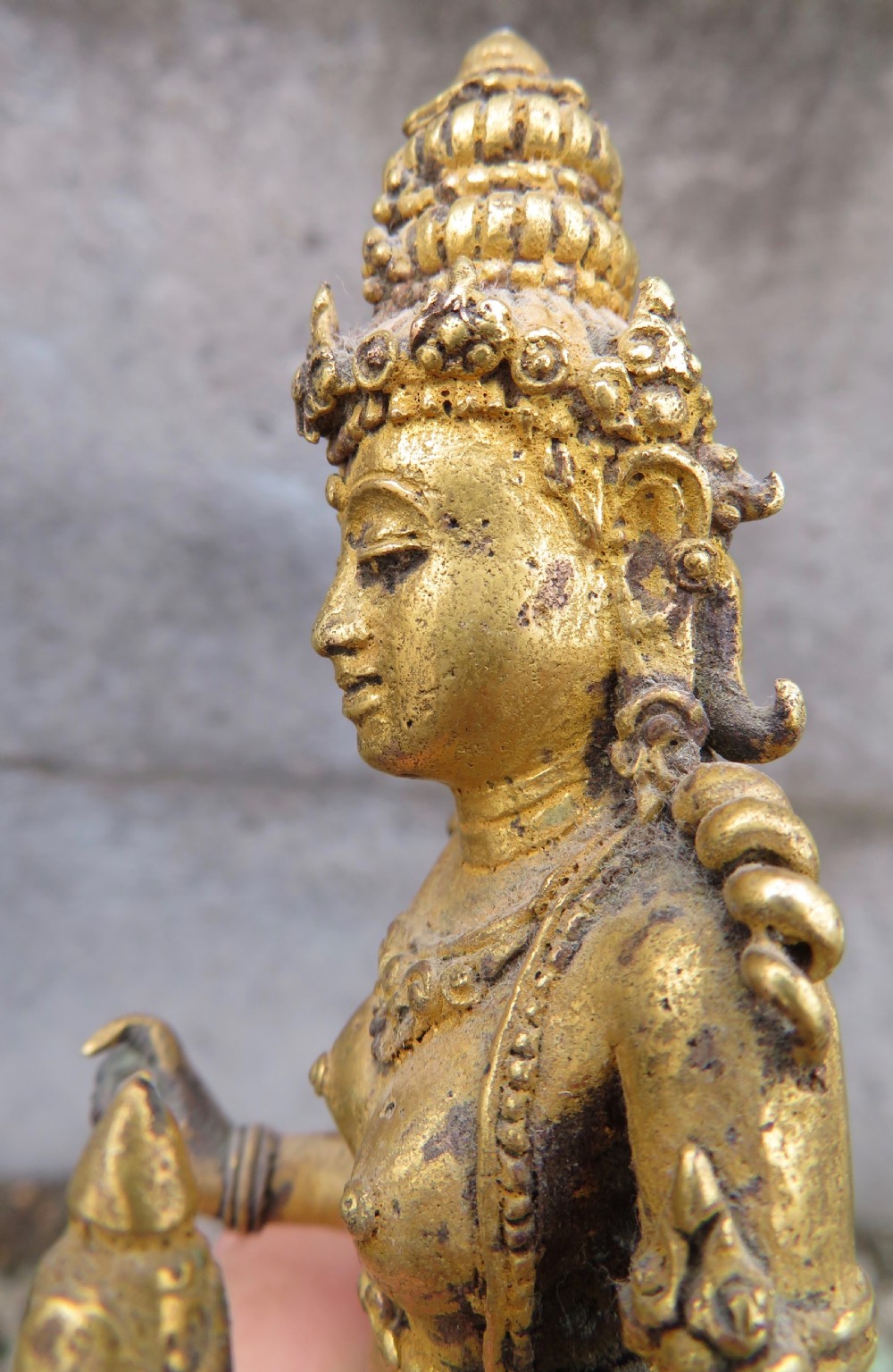 A standing gilded metal statue of a deity on a lotus base holding a lotus stem with an ornate crown and detailed jewellery. View XVIII