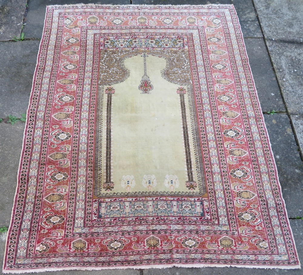 An antique Turkish Kayseri prayer rug featuring a central pale pistachio green field with a mihrab niche surrounded by intricate floral borders in coral pink and cream.