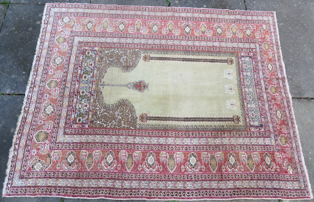 An antique Turkish Kayseri prayer rug featuring a central pale pistachio green field with a mihrab niche surrounded by intricate floral borders in coral pink and cream. View III