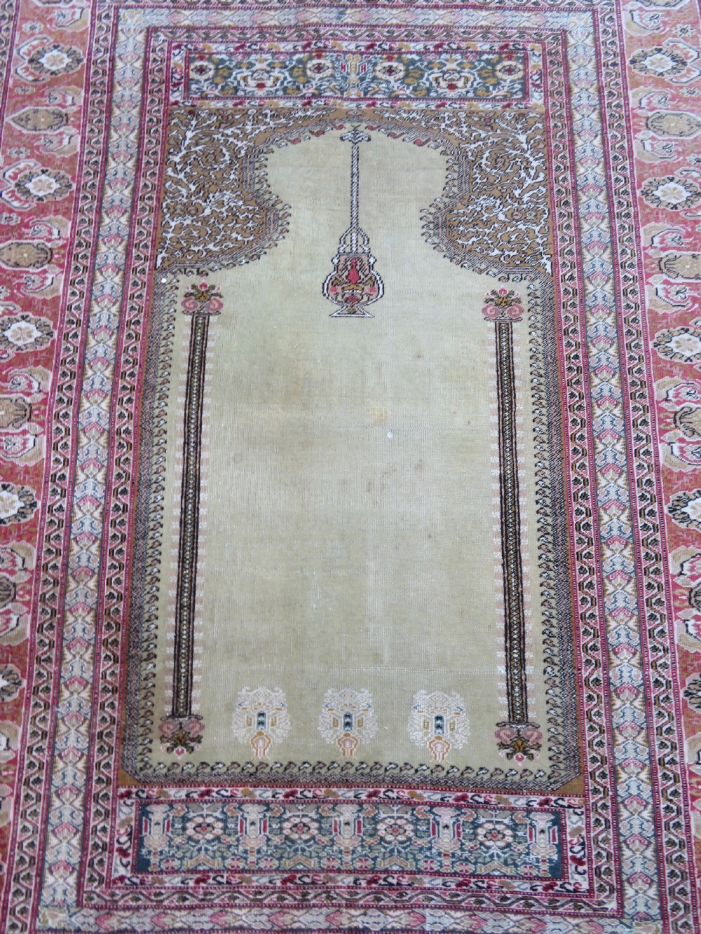 An antique Turkish Kayseri prayer rug featuring a central pale pistachio green field with a mihrab niche surrounded by intricate floral borders in coral pink and cream. View V