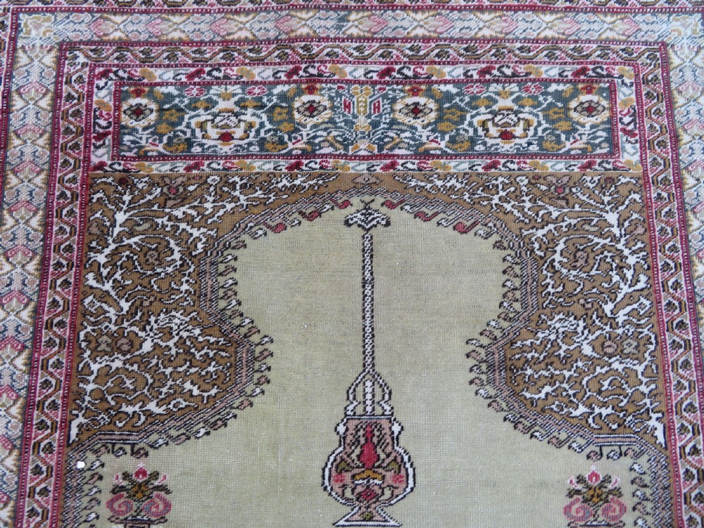 An antique Turkish Kayseri prayer rug featuring a central pale pistachio green field with a mihrab niche surrounded by intricate floral borders in coral pink and cream. View VIII
