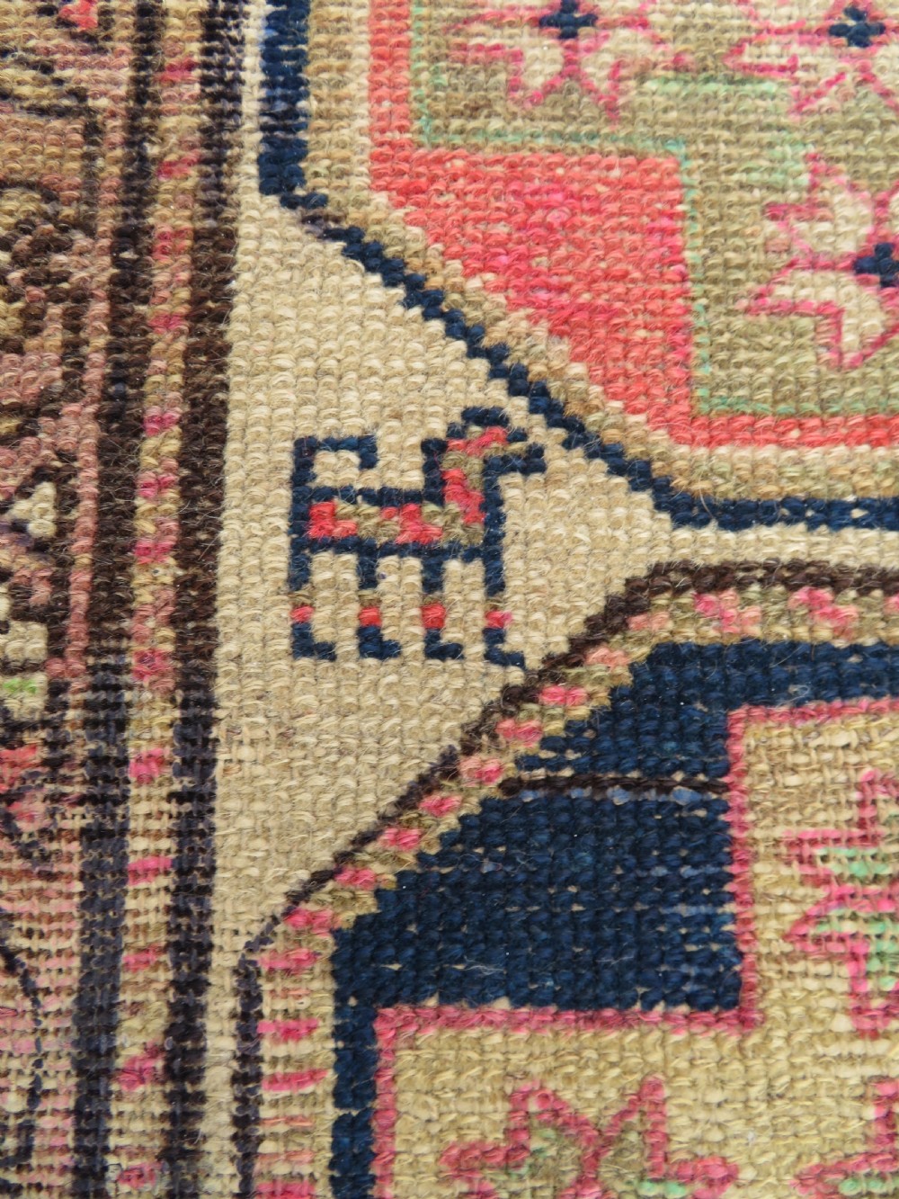 An antique Kurdish hand-knotted wool rug featuring octagonal geometric medallions, cross motifs, stylized animal figures, and a multi-banded border in rose, beige, and navy. View V