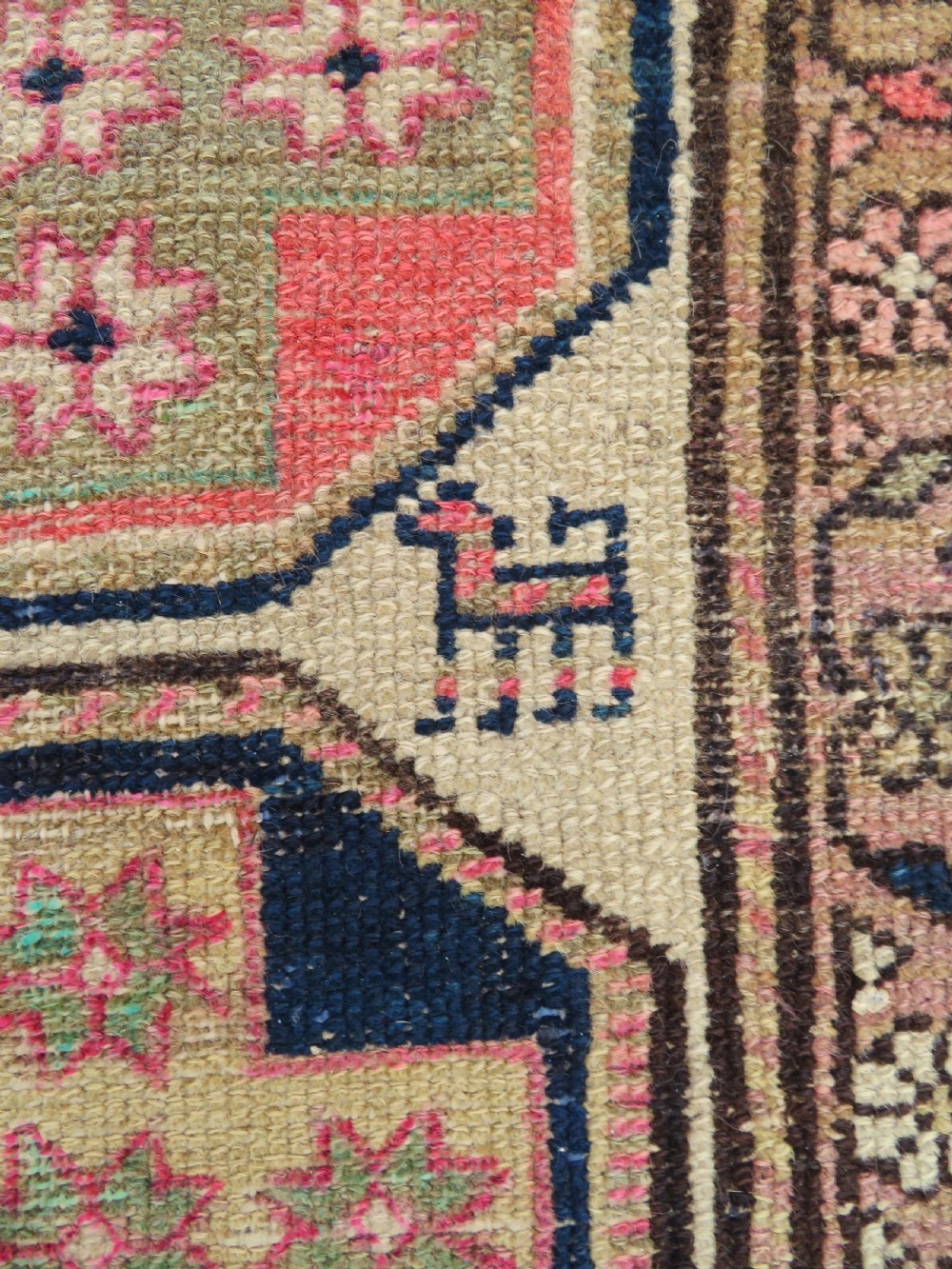 An antique Kurdish hand-knotted wool rug featuring octagonal geometric medallions, cross motifs, stylized animal figures, and a multi-banded border in rose, beige, and navy. View VI