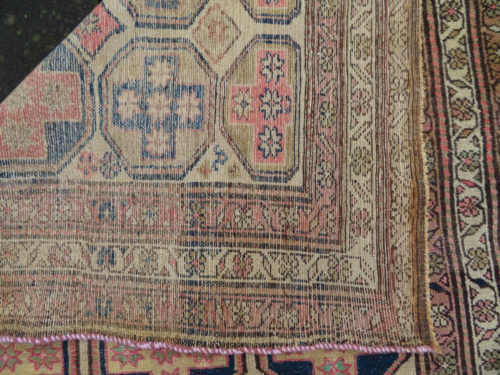 An antique Kurdish hand-knotted wool rug featuring octagonal geometric medallions, cross motifs, stylized animal figures, and a multi-banded border in rose, beige, and navy. View XVI