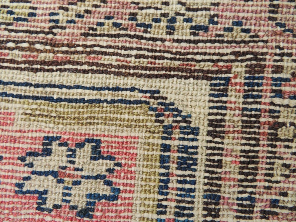 An antique Kurdish hand-knotted wool rug featuring octagonal geometric medallions, cross motifs, stylized animal figures, and a multi-banded border in rose, beige, and navy. View XVIII