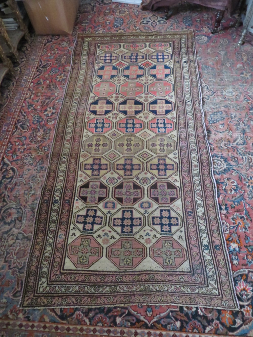 An antique Kurdish hand-knotted wool rug featuring octagonal geometric medallions, cross motifs, stylized animal figures, and a multi-banded border in rose, beige, and navy. View XXV