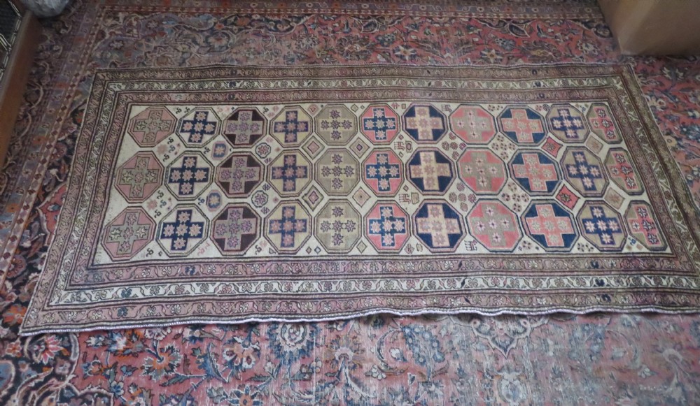 An antique Kurdish hand-knotted wool rug featuring octagonal geometric medallions, cross motifs, stylized animal figures, and a multi-banded border in rose, beige, and navy. View XXVI
