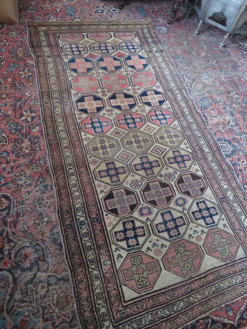 An antique Kurdish hand-knotted wool rug featuring octagonal geometric medallions, cross motifs, stylized animal figures, and a multi-banded border in rose, beige, and navy. View XXVII