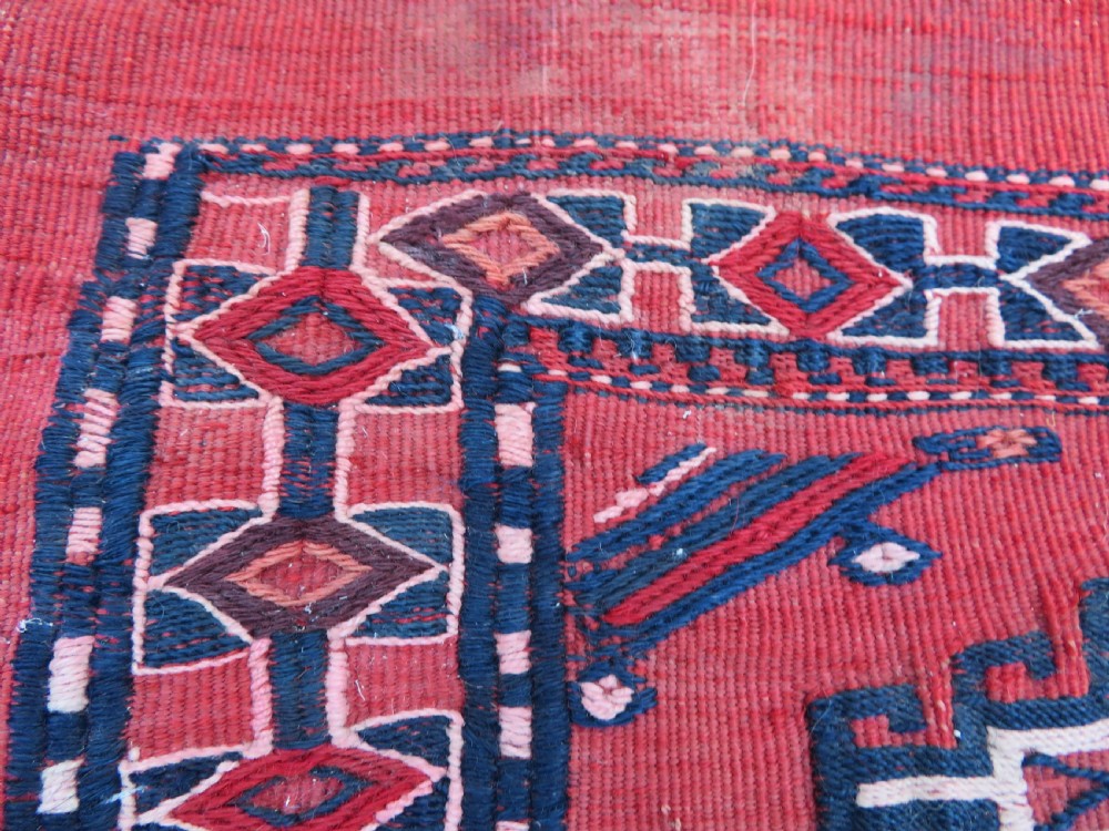 Mid-nineteenth century Turkmen chuval textile featuring repeated geometric gul medallions woven in navy blue and ivory against a crimson red field with a flat-woven lower section. View III