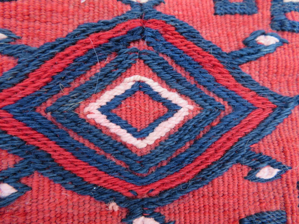 Mid-nineteenth century Turkmen chuval textile featuring repeated geometric gul medallions woven in navy blue and ivory against a crimson red field with a flat-woven lower section. View VII