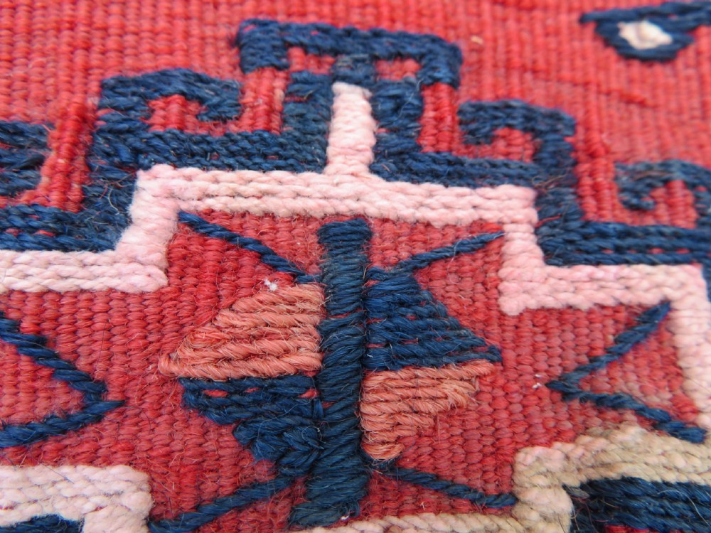 Mid-nineteenth century Turkmen chuval textile featuring repeated geometric gul medallions woven in navy blue and ivory against a crimson red field with a flat-woven lower section. View IX