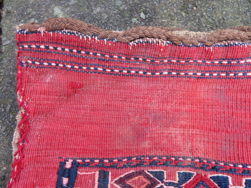 Mid-nineteenth century Turkmen chuval textile featuring repeated geometric gul medallions woven in navy blue and ivory against a crimson red field with a flat-woven lower section. View XII