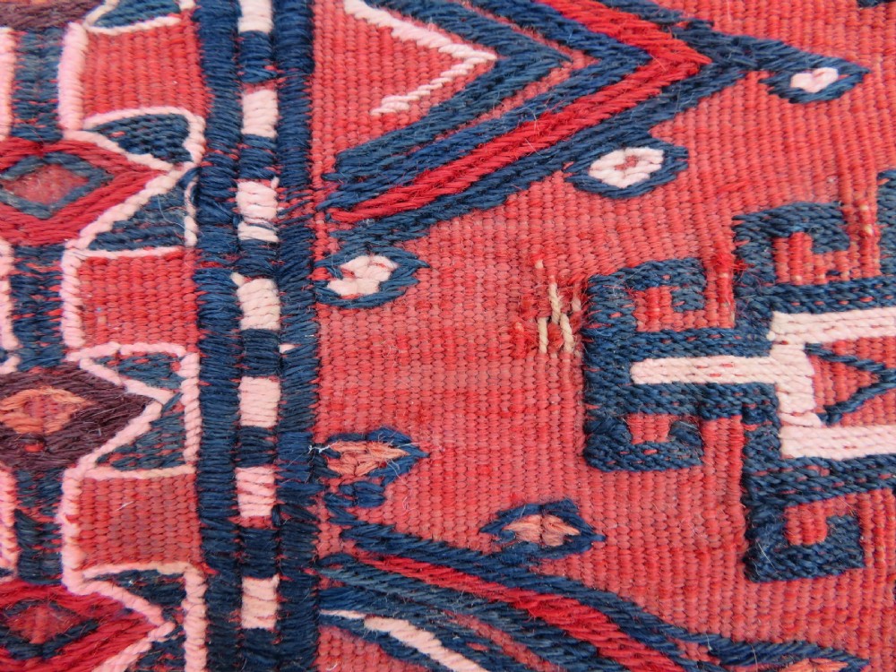 Mid-nineteenth century Turkmen chuval textile featuring repeated geometric gul medallions woven in navy blue and ivory against a crimson red field with a flat-woven lower section. View XIII