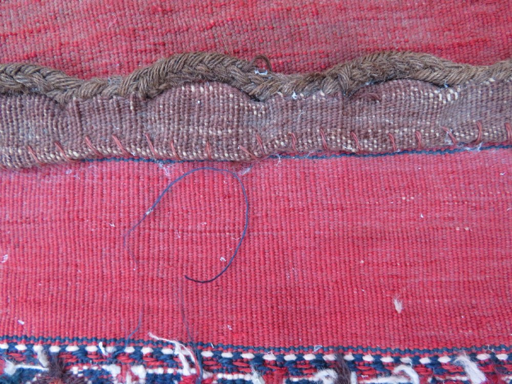 Mid-nineteenth century Turkmen chuval textile featuring repeated geometric gul medallions woven in navy blue and ivory against a crimson red field with a flat-woven lower section. View XV