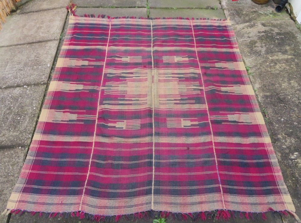 A rectangular flat-woven wool textile featuring crimson, navy, and cream geometric checked patterns with fringed ends. View II