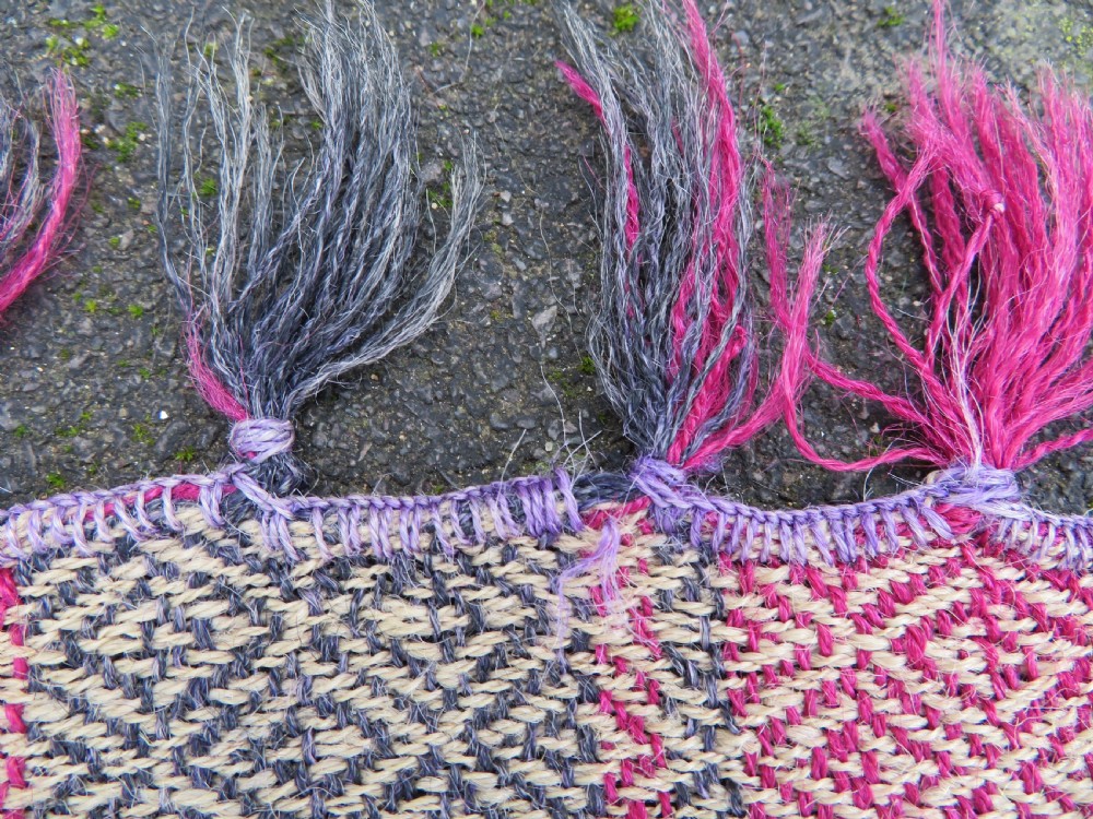 A rectangular flat-woven wool textile featuring crimson, navy, and cream geometric checked patterns with fringed ends. View XIII