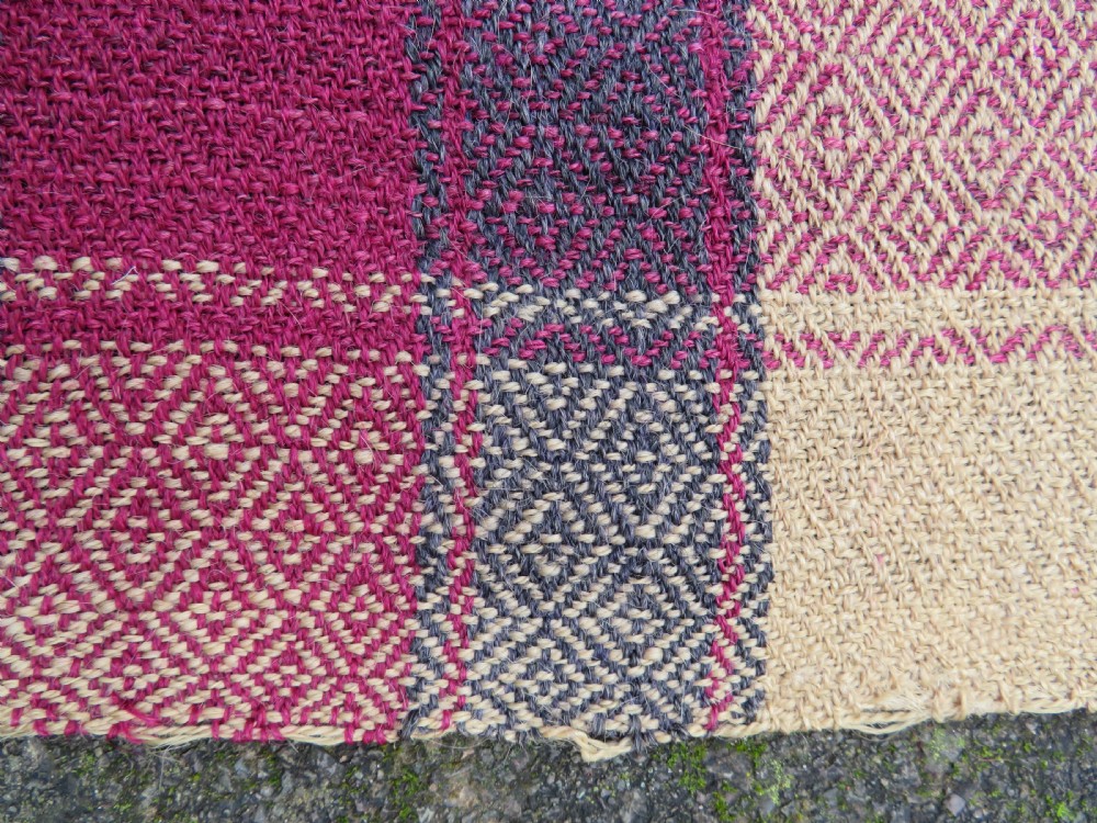 A rectangular flat-woven wool textile featuring crimson, navy, and cream geometric checked patterns with fringed ends. View XVII