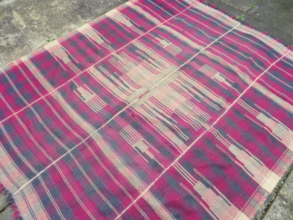 A rectangular flat-woven wool textile featuring crimson, navy, and cream geometric checked patterns with fringed ends. View XIX