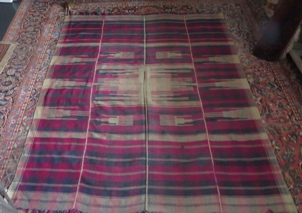 A rectangular flat-woven wool textile featuring crimson, navy, and cream geometric checked patterns with fringed ends. View XXVI