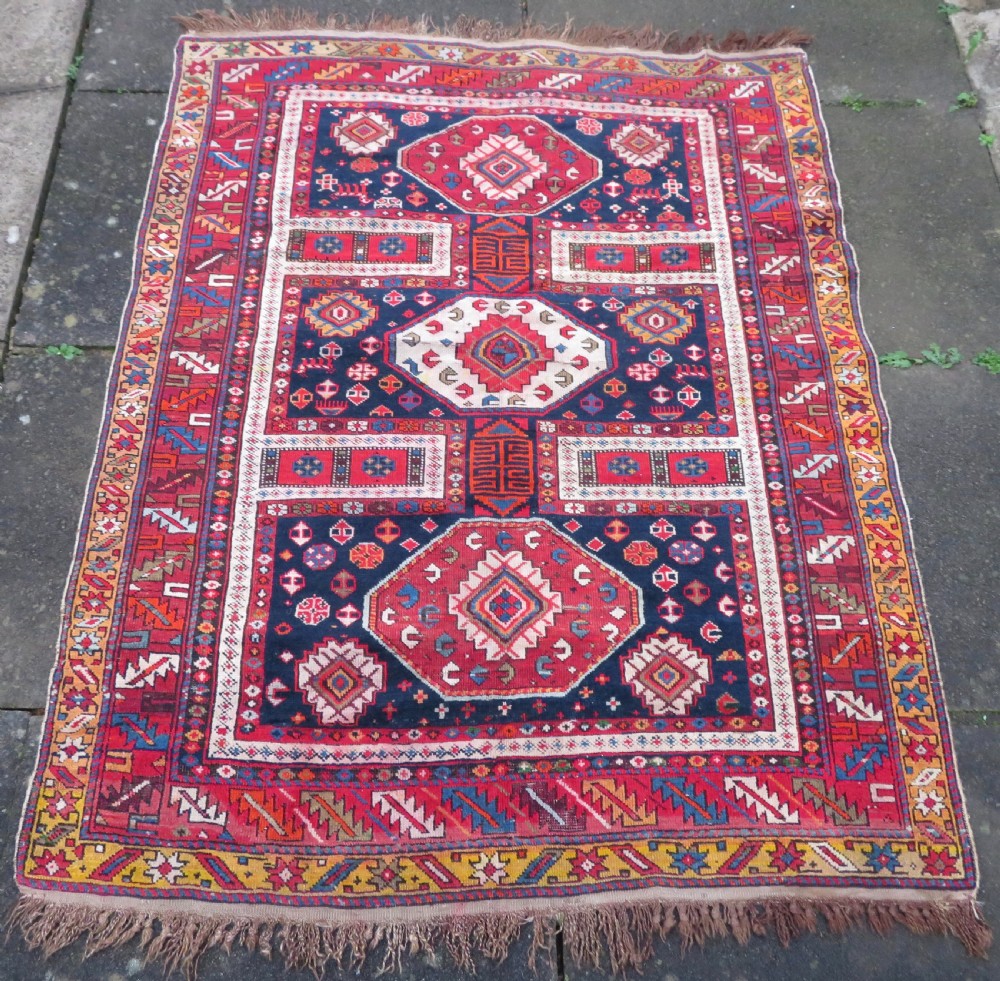 An antique late 19th-century Caucasian Kuba Konagkend wool rug featuring red geometric medallions set against a dark navy field with multi-coloured borders. View II